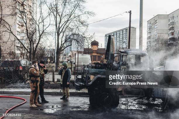 Ukrainian soldiers look at their burnt-out army military vehicle on February 25 in Kiev, Ukraine. Russian soldiers have entered Kiev to carry out...