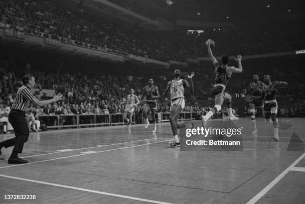 76ers' Wally Jones leaps high to intercept down court pass for Celtics' Bill Russell during 1st period action, 6th NBA Eastern playoff game, Boston...