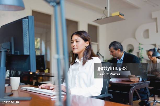 personas que trabajan en sus respectivos escritorios en un lugar de trabajo moderno - filipino ethnicity and female not male fotografías e imágenes de stock
