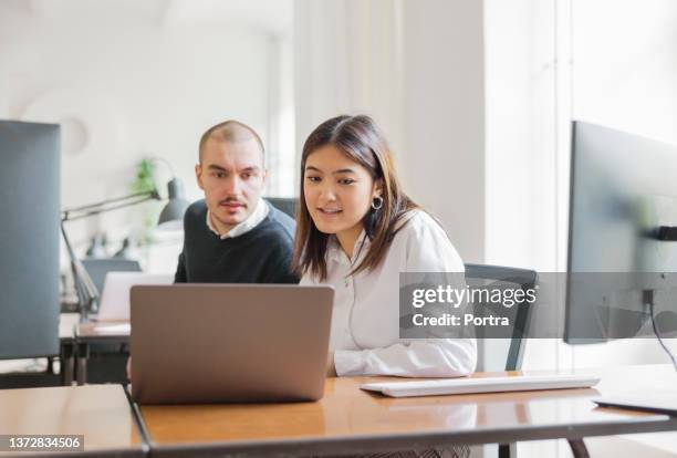 office colleagues working together in office - woman laptop screen stockfoto's en -beelden