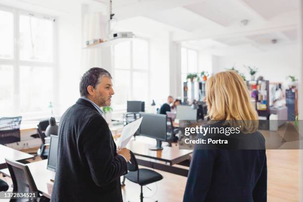 unternehmerinnen und unternehmerinnen diskutieren, während sie gemeinsam im büro spazieren gehen - managing director stock-fotos und bilder