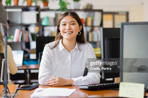 portrait of a confident asian businesswoman at her desk - filipino stockfoto's en -beelden