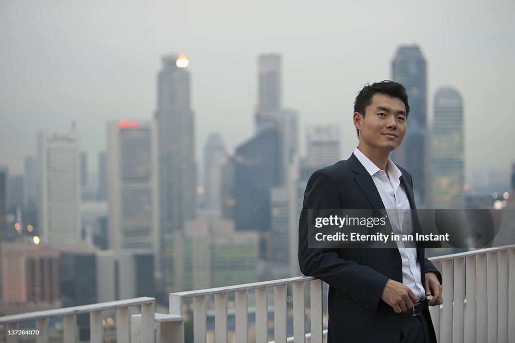 Businessman smiling with city, background at dusk