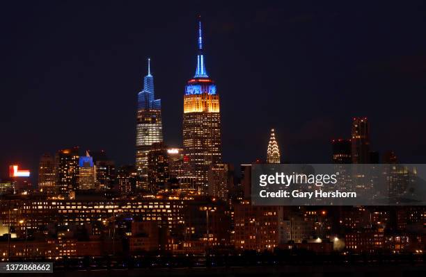 The Empire State Building is lit in the colors of the flag of Ukraine in New York City on February 25, 2022 as seen from Jersey City, New Jersey.