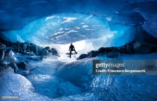 alpinist looks the sunrise from a ice glacier cave. morteratsch glacier, canton of graubunden(grisons), switzerland, europe. - crampon stock pictures, royalty-free photos & images