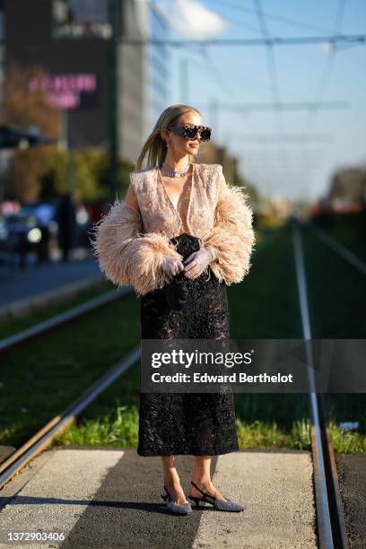 Leonie Hanne wears black and beige monogram print pattern futurist sunglasses from Gucci, silver pendant earrings, a silver chain with letter pendant...