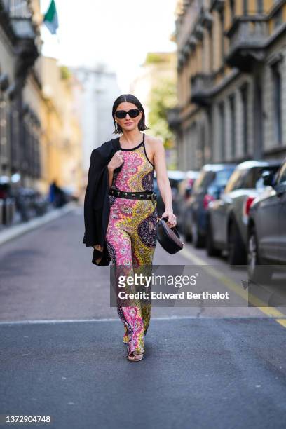 Alexandra Pereira wears black sunglasses, gold earrings, a black blazer jacket from Etro, a yellow / pink / purple with black and white print pattern...