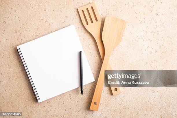 blank notepad and pen and wooden kitchen utensils from above, top view. shopping list, grocery list, recipe - kochbuch stock-fotos und bilder