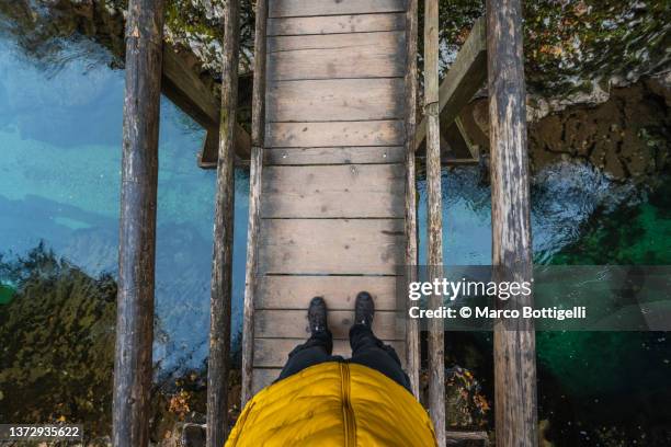 personal perspective of person walking on a wooden bridge over a river - looking above stockfoto's en -beelden