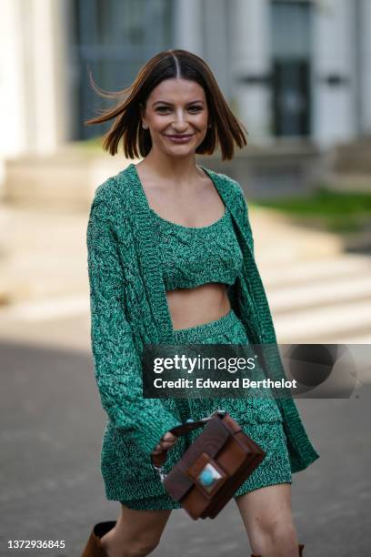 Guest wears earrings, a green braided wool V-neck / cropped tank-top, matching green braided wool oversized cardigan, a matching green braided wool...