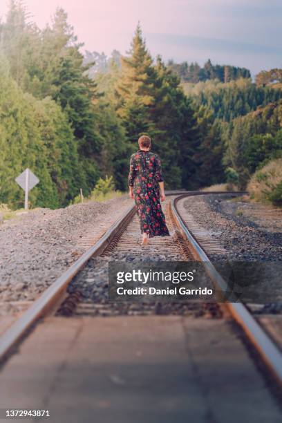 girl walking along the train tracks, girl with a dress and barefoot, feeling free in new zealand - level crossing stock pictures, royalty-free photos & images