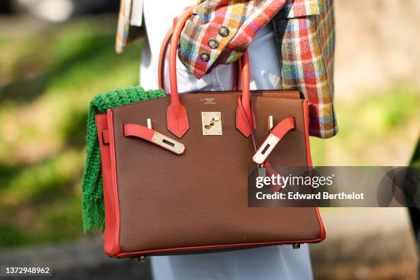 Guest wears a green embossed print pattern scarf, a red / yellow / blue / green checkered print pattern blazer jacket, a brown and orange shiny...