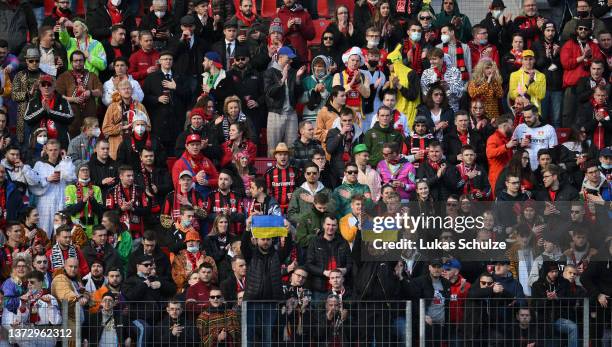 Bayer 04 Leverkusen fans raise Ukraine flags as Players, officials and fans take part in a minute of silence to indicate peace and sympathy with...