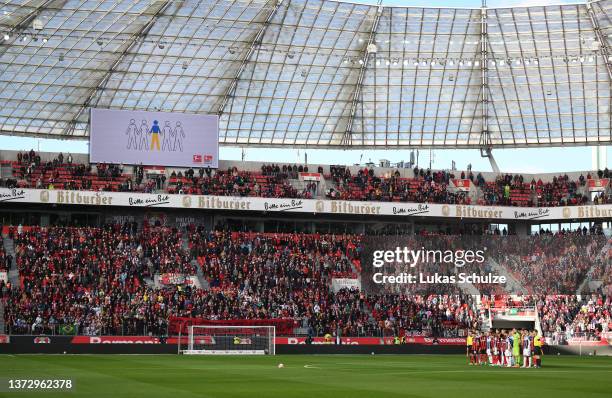 General view as Bayer 04 Leverkusen and DSC Arminia Bielefeld stand together as Players, officials and fans take part in a minute of silence to...