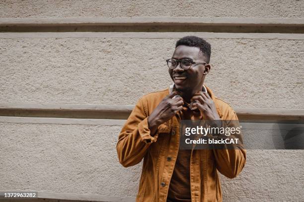 porträt eines jungen selbstbewussten afroamerikanischen mannes vor der wand - global fashion collective stock-fotos und bilder
