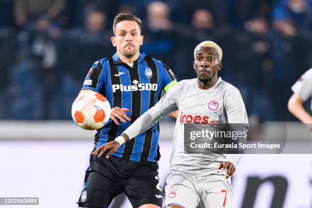 Henry Onyekuru of Olympiacos is chased by Rafael Tolói of Atalanta during the UEFA Europa League Knockout Round Play-Offs Leg One match between...