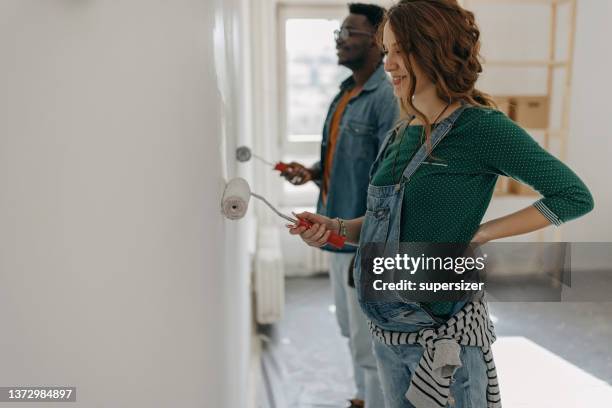 schwangere junge frau malt zusammen mit ihrem mann kinderzimmer - couple painting stock-fotos und bilder