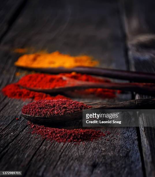 set of asian spices in authentic wooden spoons side view on old wooden board background closeup. selective focus, macro - dry vegetables stock-fotos und bilder