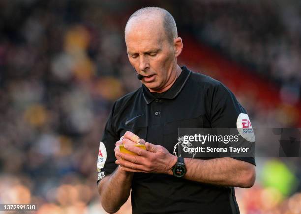 Referee Mike Dean writes on his yellow card during the Premier League match between Brentford and Newcastle United at Brentford Community Stadium on...