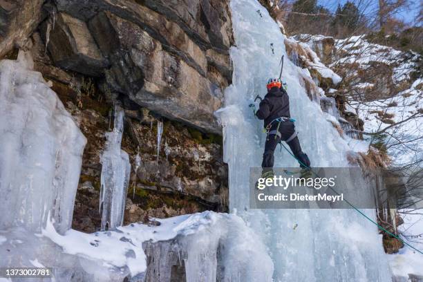 male ice climber climbing frozen cascade - safety harness stock pictures, royalty-free photos & images