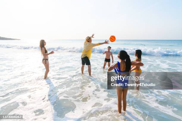 children with parent playing beach ball in the sea - girls beach volleyball stock pictures, royalty-free photos & images