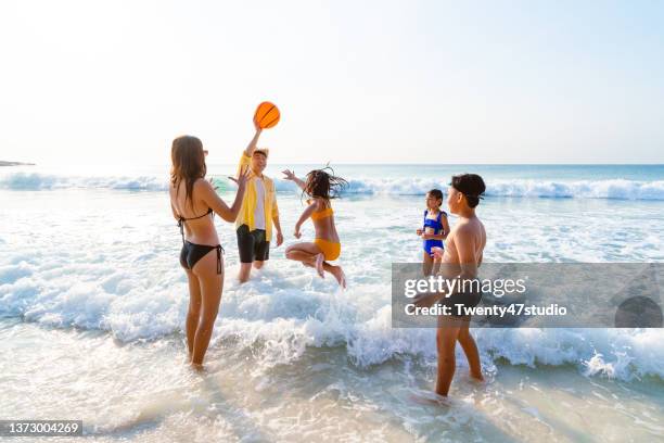 children with parent playing beach ball in the sea - girls beach volleyball stock pictures, royalty-free photos & images