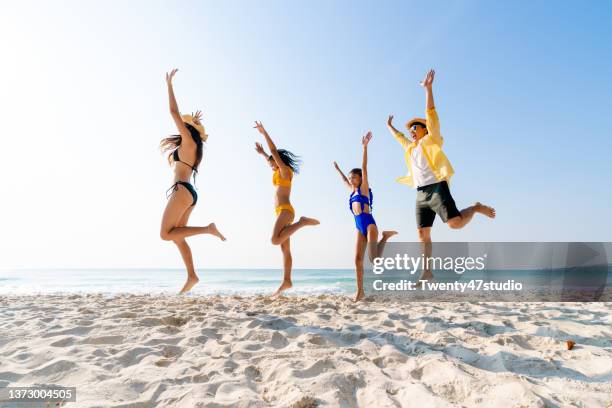 happy asian family enjoying summer vacation on the beach - beach family jumping stock pictures, royalty-free photos & images