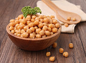 Wooden bowl overflowing with chickpeas topped with parsley