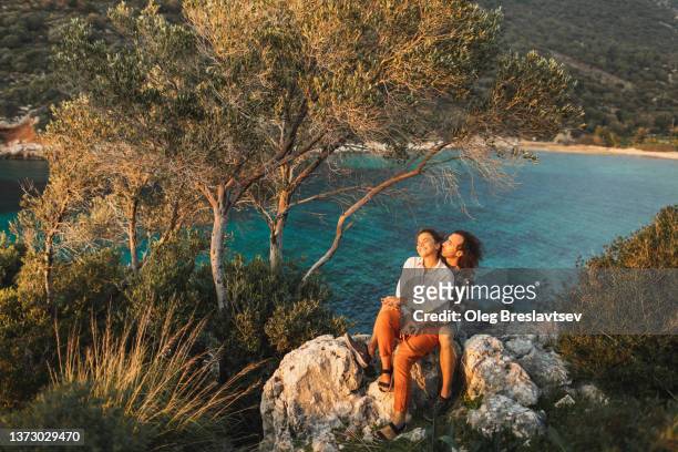 Young happy couple hugging and laughing with amazing sea and mountain coastline view. Romantic feelings and love