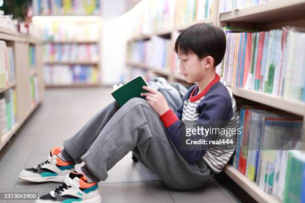 cute boy reading book in library - child reading a book stock pictures, royalty-free photos & images