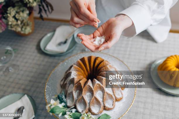 unrecognizable female pastry chef decorating a delicious bundt cake with powdered sugar - bundt cake stock pictures, royalty-free photos & images