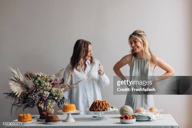 two smiling female friends having fun while setting the table for a birthday party - happy birthday flowers images stock pictures, royalty-free photos & images