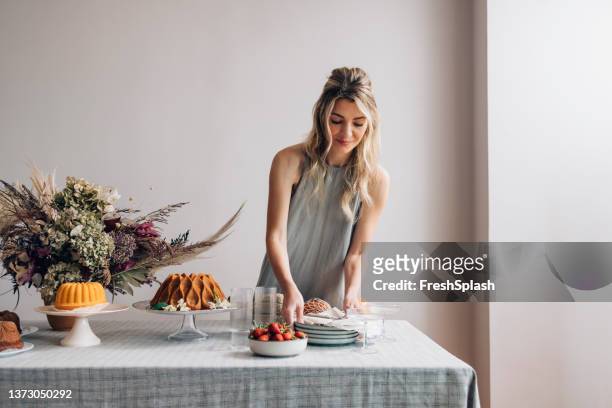 schöne blonde frau deckt den tisch für eine geburtstagsfeier - woman making cake stock-fotos und bilder