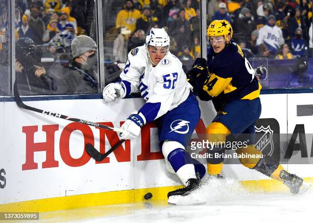 Cal Foote of the Tampa Bay Lightning and Tanner Jeannot of the Nashville Predators vie for the puck along the side boards during the second period of...