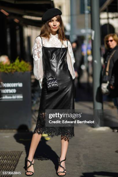 Mara Lafontan wears a black felt beret, a white lace print pattern high neck / puffy sleeves blouse, a black shiny leather square-neck / tank-top...