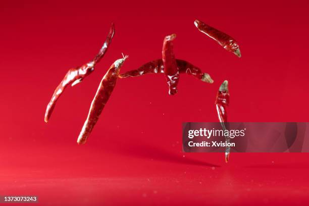 dry red chilli flying in mid air in red background - dry vegetables stock-fotos und bilder