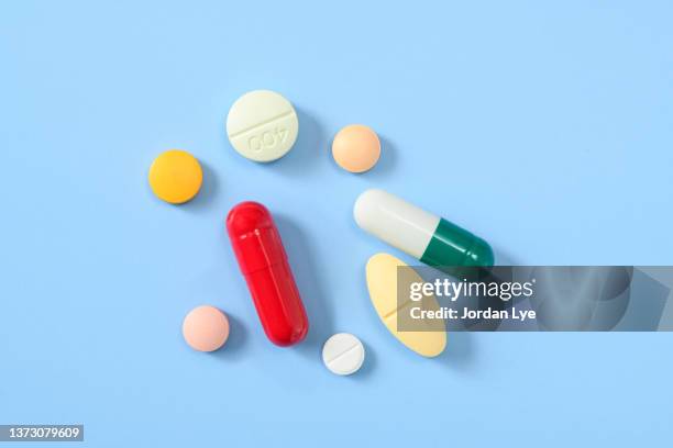 flat lay of various pills and tablets on the blue background - drug stock-fotos und bilder