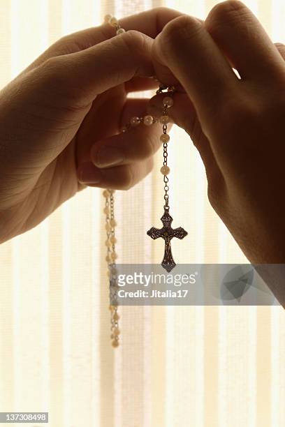 hände holding rosenkranz in confessional booth - a cross necklace stock-fotos und bilder