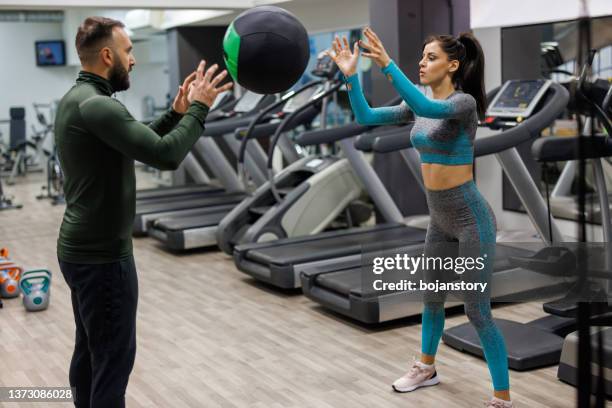 young man and woman working out with a fitness ball in a gym - medicine ball stock pictures, royalty-free photos & images