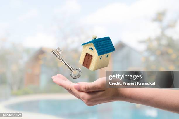 real estate agent, broker, businesswoman is holding a small yellow house with key  for sale, buying, protecting, renting real estate - real estate sign fotografías e imágenes de stock