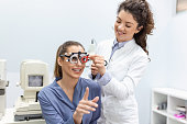 Optometrists changes lenses in trial frame to examine the vision of young woman patient vision at ophthalmology clinic, selective focus