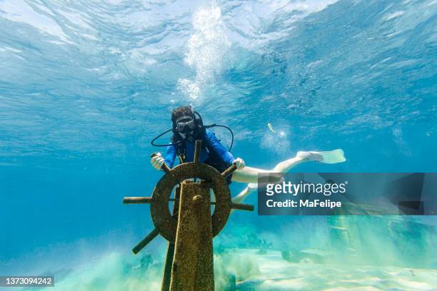 teenage scuba diver girl holding a ship helm from a wreckage  at the bottom of the sea - scuba diving girl 個照片及圖片檔