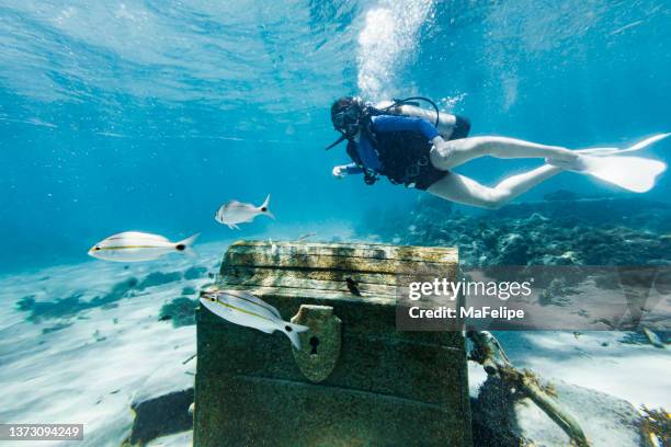 teenage girl scuba diving over a pirate chest on the bottom of the sea - treasure stock pictures, royalty-free photos & images