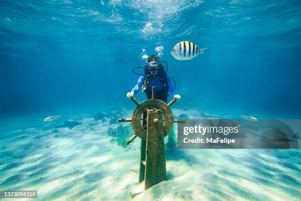 teenager-tauchermädchen mit einem schiffshelm aus einem wrack auf dem meeresgrund - shipwreck stock-fotos und bilder