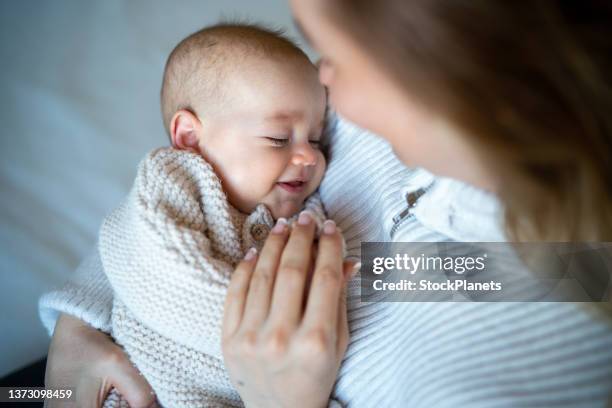 frau, die ihr kleines mädchen zu hause trägt - baby smiling stock-fotos und bilder