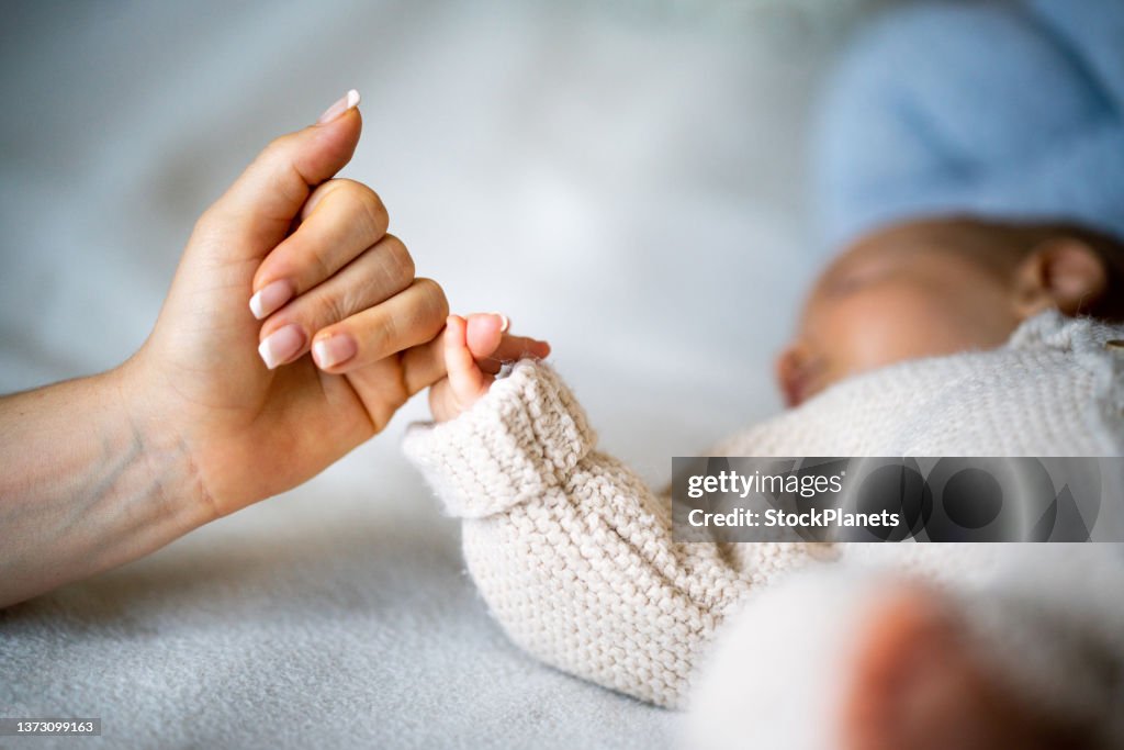 Hand hält Neugeborenebaby Hand