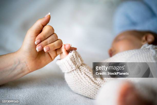 hand holding newborn baby's hand - baby's stockfoto's en -beelden