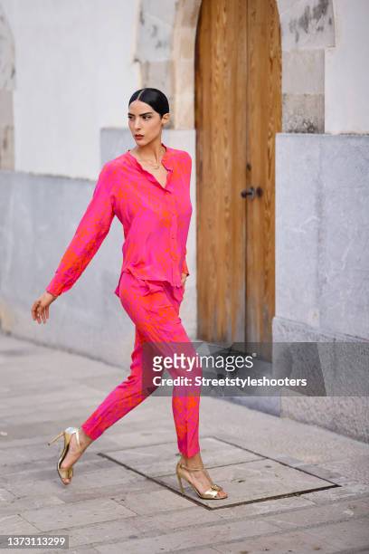 Model Zoe Helali, wearing a pink and orange blouse with abstract pattern and matching pants by zaaz design, a gold layered ring with multicolored...