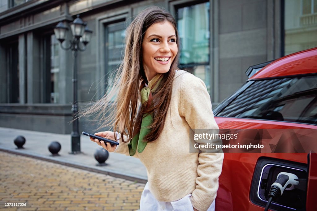 Portrait of woman charging her electric car