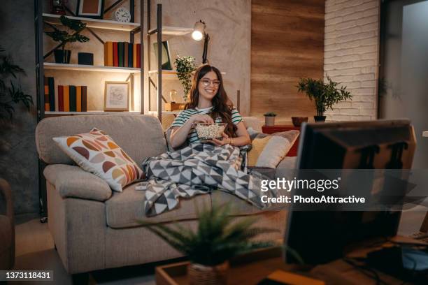 ソファの上の夜にテレビを見ている女性 - one person time ストックフォトと画像
